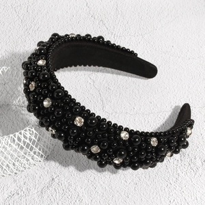 Serre-tête vintage noir en éponge avec perles et strass sur fond beige texturé