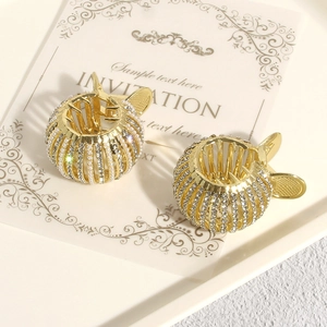 Golden round claw clips with pearls and rhinestones shown from a 45-degree angle