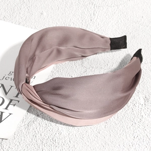 Detailed view of dust pink satin knotted headband with soft texture and cushioned ends