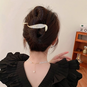 Elegant gold feather hair claw with rhinestones shown on a woman's hair bun