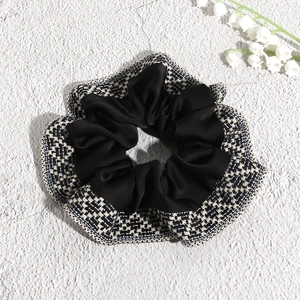 Close-up of bohemian scrunchie with black fabric and chic black and white plaid trim