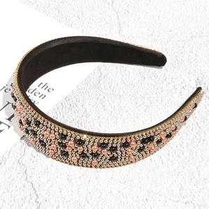 Macro shot of faux pearl and rhinestone beaded patterns on a baroque style wide headband