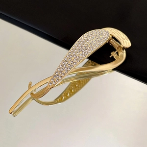Detailed macro view of a gold-tone hair clip with rhinestones and elegant curved design