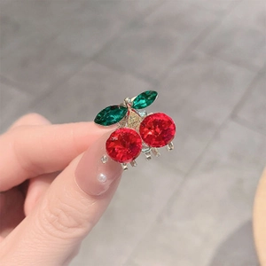 Gros plan d'une petite pince à cheveux cerise avec des cristaux rouges et verts étincelants