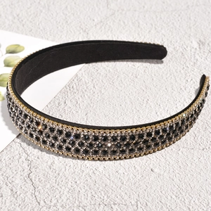 Close-up of black wide headband with rows of sparkling rhinestones and crystal beads