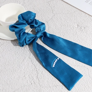 Elastico per capelli in raso blu pavone con nastro lungo e perle su superficie in pietra