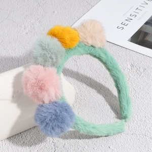 Cute plush headband with five colorful faux fur pom poms and soft green velvet base