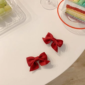 Gros plan de petites barrettes à nœuds en tissu rouge foncé avec une texture de tissu fin