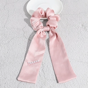 Vista dettagliata di un elastico in raso rosa con nastri eleganti e perle bianche