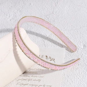 Détail d'un serre-tête en résine rose avec paillettes et strass sur support blanc