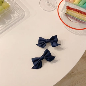 Détails de barrettes à cheveux à nœuds en tissu bleu marine sur fond de dessert