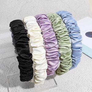 Five assorted pleated satin headbands in pastel colors displayed on acrylic stand