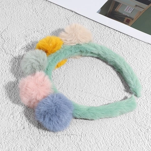 Cute mint green plush headband with five colorful faux rabbit fur balls on stone surface