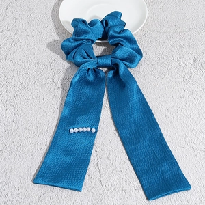 Dettaglio dell'elastico in raso blu pavone con nastro lungo e perle bianche applicate