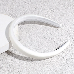 Detail of a thick white satin padded headband on a minimalist display stand