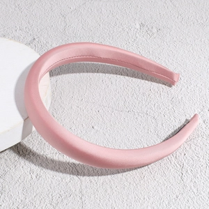 Detailed close-up of a pink satin sponge headband showing smooth silky texture and stitching