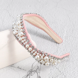 Détail d'un serre-tête en tissu rose avec perles et strass sur support en céramique