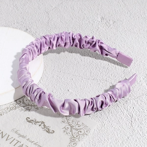 Detail view of light purple pleated satin headband with smooth silky texture and soft luster