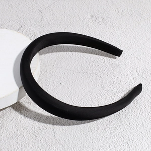 Detail of a padded black satin headband with a smooth glossy texture and thick sponge foam