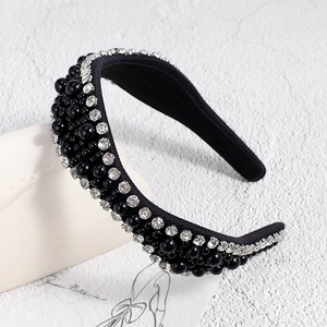 Détail d'un serre-tête en tissu noir avec perles synthétiques et strass brillants