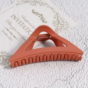 Close-up of matte brick red triangular hair claw clip with wide teeth and metal spring