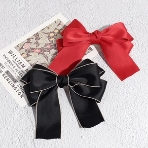 Elegant French satin oversized bow hair clips in vibrant red and gold-edged black colors