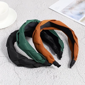 Detail of elegant braided headbands in black, dark green, and caramel satin finish