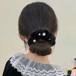 Détail d'un chouchou en peluche noire avec perles porté sur un chignon élégant