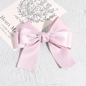 Close-up of elegant double-layered pink satin bow hair clip on a textured surface