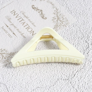 Close-up of a cream triangle claw clip with a gold spring on an invitation card