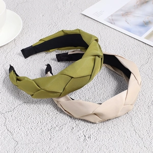 Detailed close-up of woven satin headbands in olive green and beige on a stone surface