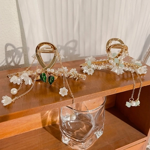 Detail of lily of the valley hair claw with pearl tassels on a wooden stand