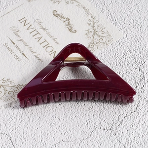 Detail view of burgundy triangle hair claw clip with golden spring and glossy finish