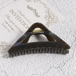 Detailed view of large dark brown translucent triangular hair claw with a gold metal spring