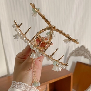 Detailed macro view of golden lily of the valley hair claw with pearls and tassels
