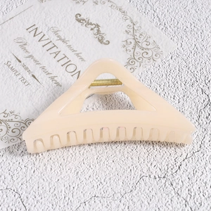 Detail view of cream resin triangle hair claw clip with golden spring and matte finish