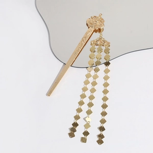Detail of elegant gold tassel hair stick featuring metallic square fringes on white surface