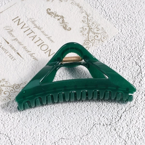 Detail shot of a dark green triangular hair claw clip with golden metal spring