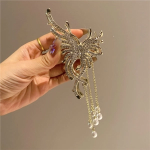 Detail of golden butterfly hair claw with sparkling rhinestones and pearl tassels