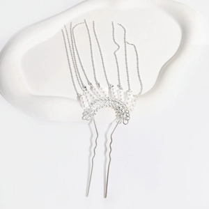 Close-up of silver metal hair pin with pearls and long tassel on a white tray