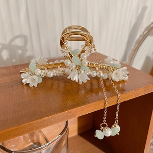 Detail of lily of the valley hair claw with pearl tassels and golden metal finish