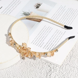 Detail view of gold crystal headband with champagne floral beadwork on white marble base