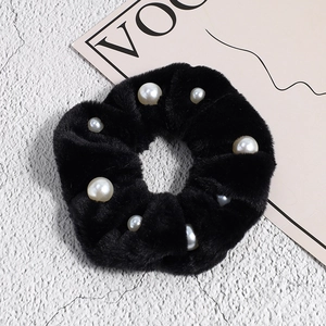 Détail d'un chouchou en peluche noire avec d'élégantes décorations en perles