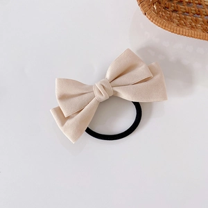 Close-up of a beige double-layered bow hair tie with premium matte texture and black elastic