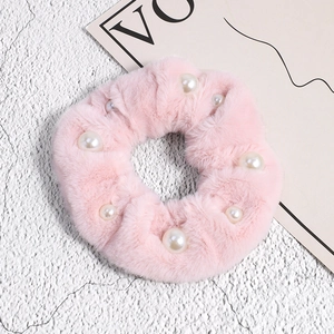 Détail du chouchou en peluche rose avec perles élégantes et texture douce