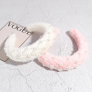 Winter plush headband with faux pearls in white and pink on a textured stone surface