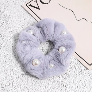 Détail d'un chouchou en peluche lavande avec fausse fourrure douce et perles blanches