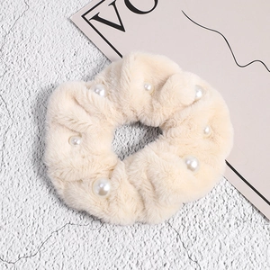 Gros plan sur un chouchou en fausse fourrure beige avec perles blanches et texture douce