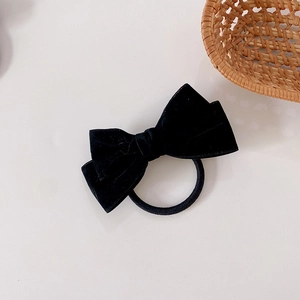 Detail of a black velvet bow hair tie with a flexible elastic band for women hair styling