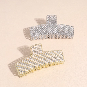 Elegant pearl and rhinestone shark hair clips in gold and silver finishes on beige surface